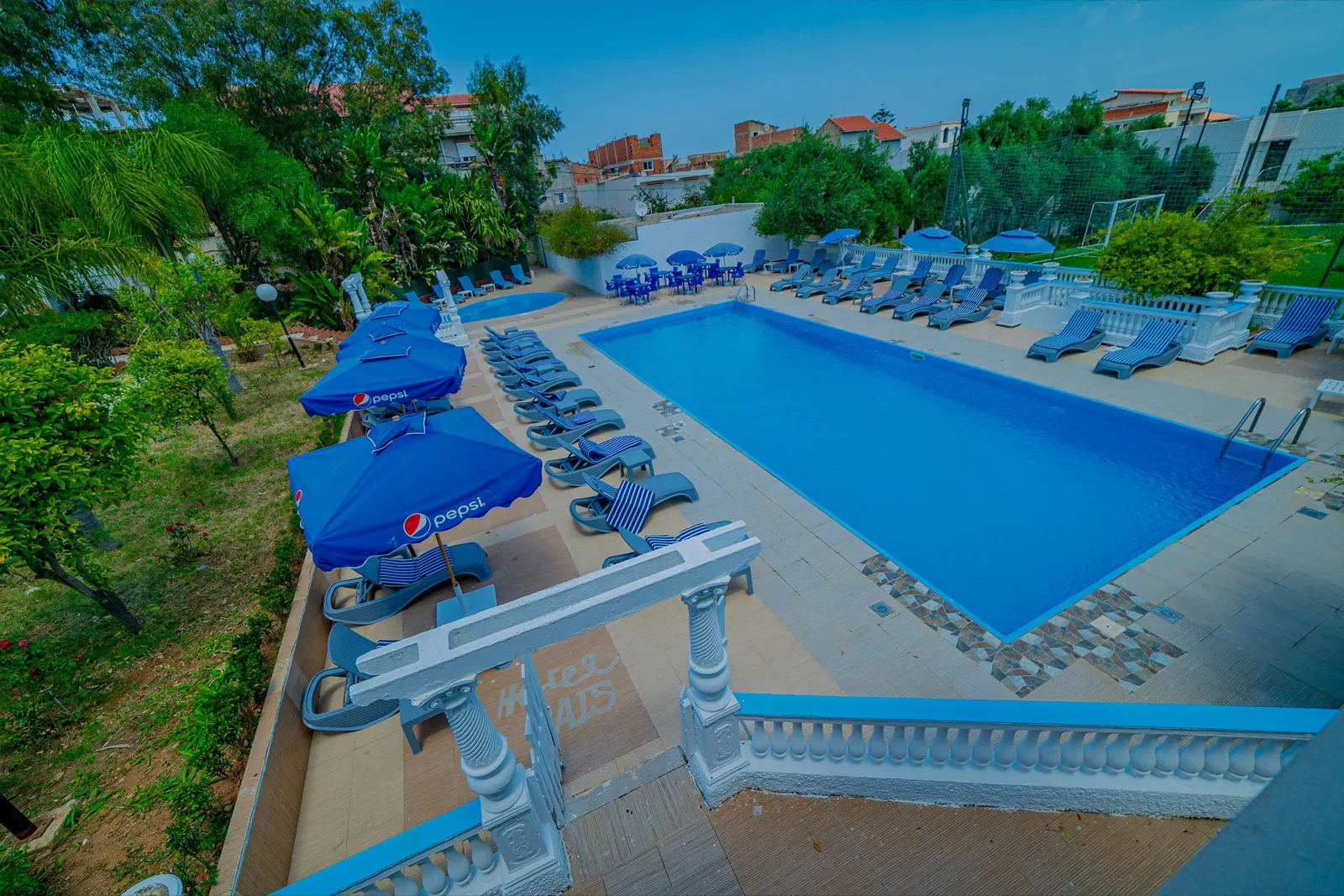 Vue d'ensemble de la piscine et des transats de l'Hôtel Raïs